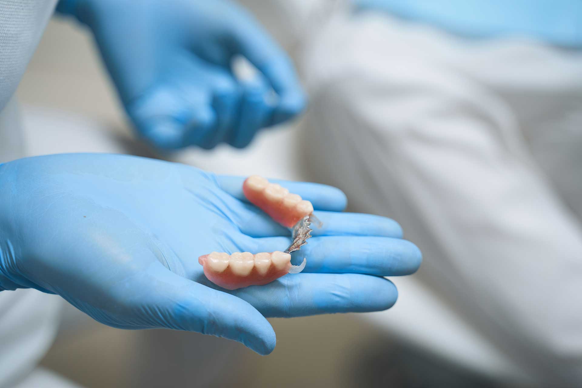 dentist-holding-dentures-in-blue-protective-gloves-2026-09-24-08-09-57-utc_1920 Dental2Ju Zahnersatz Dresden
